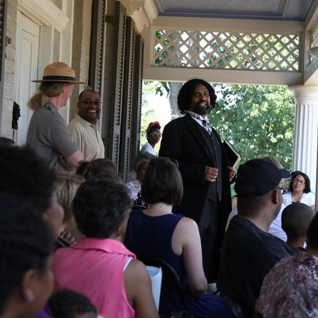 An actor dressed as Frederick Douglass talks to a crowd