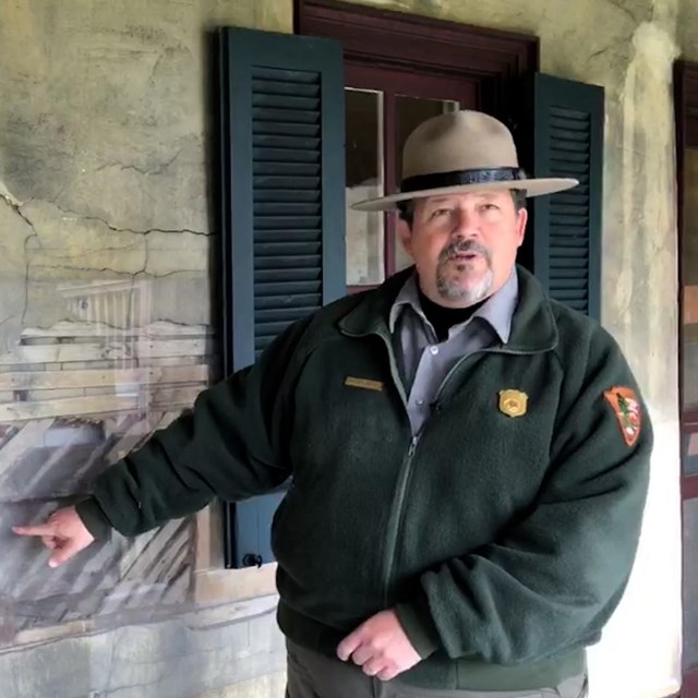 Ranger standing by exhibit exposing elements within a wall
