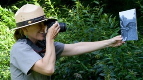 Photograph of Ranger holding a historic photograph and digital camera