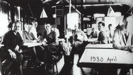 Black and white of group of men sitting around tables