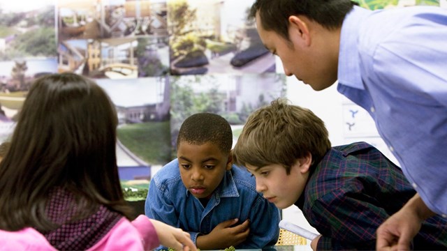 Students discuss a model of a park with a Landscape Architect