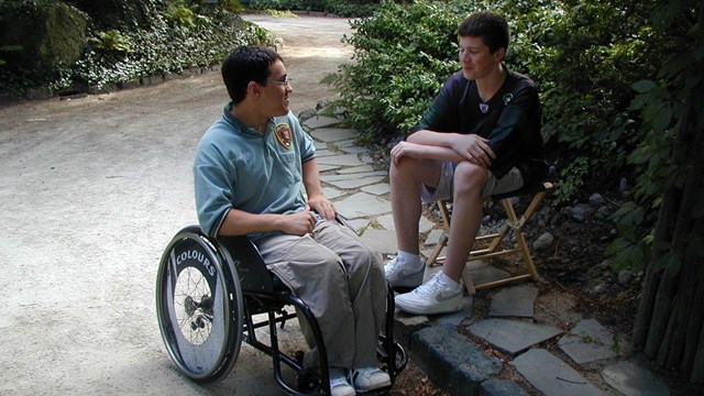 Volunteer in wheelchair talking with visitor outside