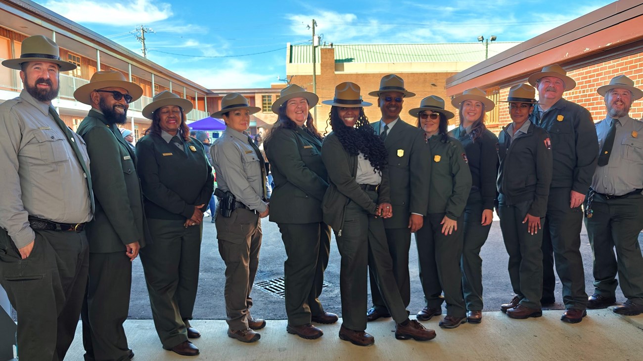 A group of rangers stands in front of a historic two story motel.
