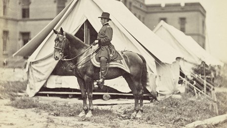 Civil War photograph of General Hooker on horseback in an urban camp.
