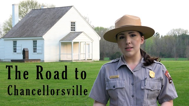 A park ranger in front of a white house with text, road to chancellorsville