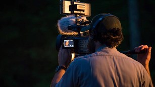 Man holding camera with microphone in darkness