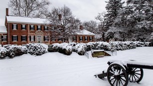 Chatham Manor's riverside terraces, lawn and cannon covered with snow.