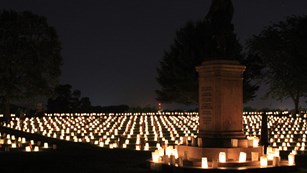 Night scene with luminaria surrounding a large monument in the Fredericksburg National Cemetery.