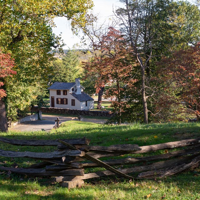 A view of a small white house from atop a hill.