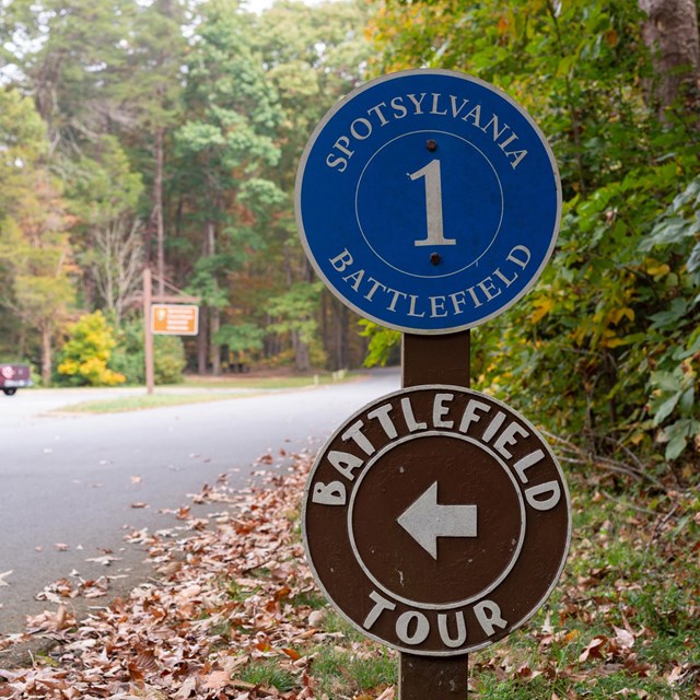 Two, stacked circular signs directing people on a Battlefield Tour.