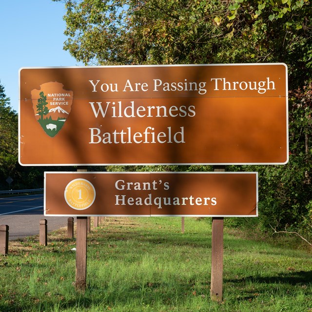 A park sign on brown background next to a highway.