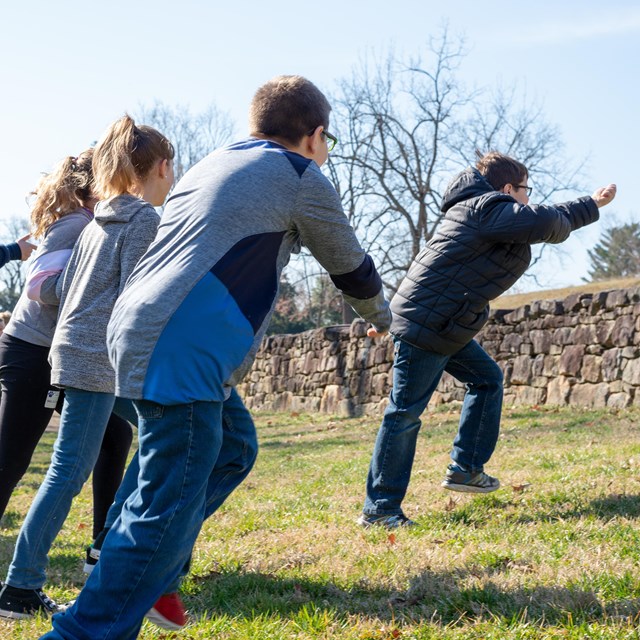 A group of children charge a stone wall.