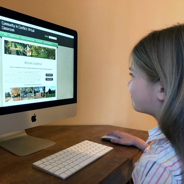A color photograph of a 9 year old girl looking at a computer screen.
