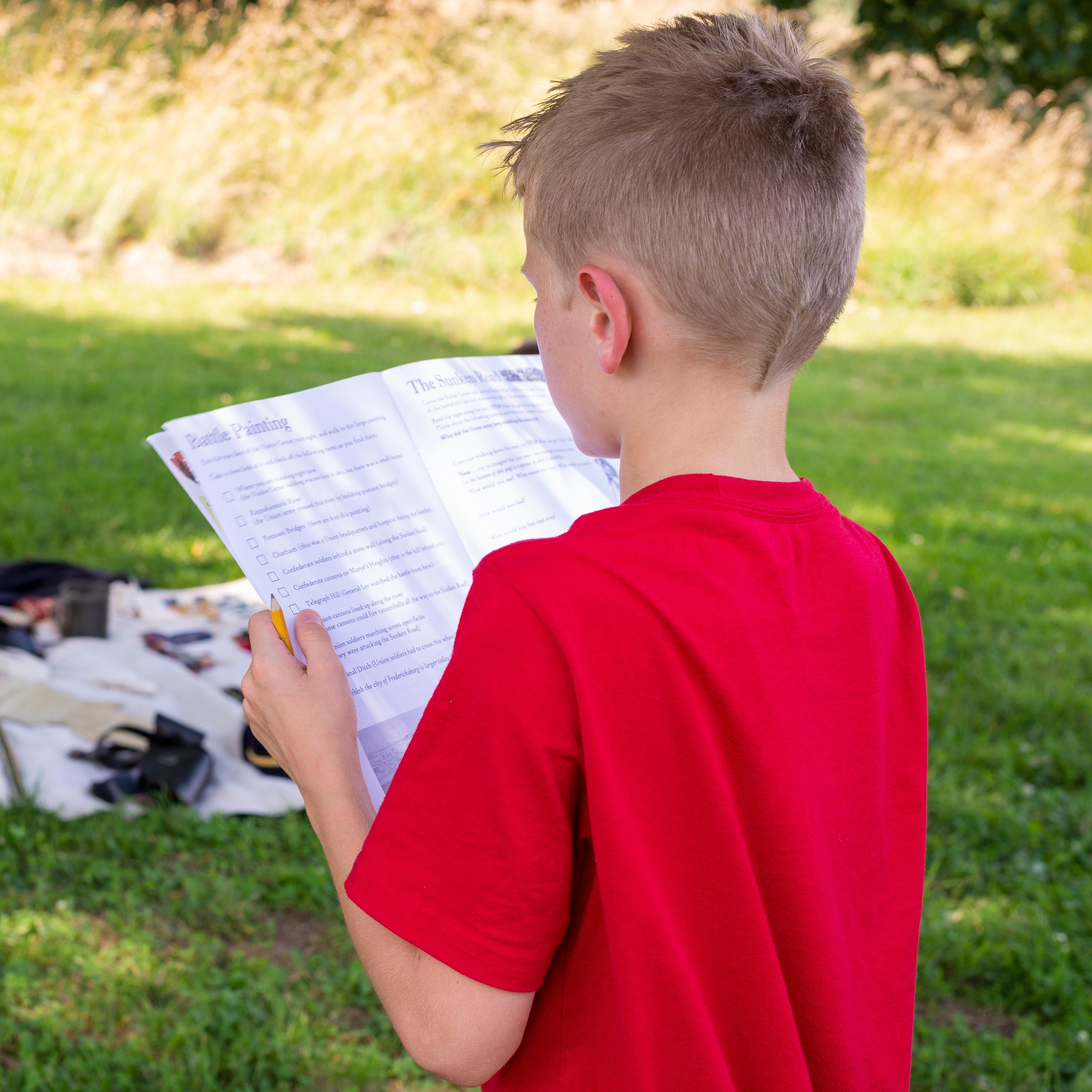 An 11 year old boy filling out a work book.