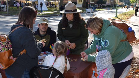A park ranger helps a group make corn husk dolls. 