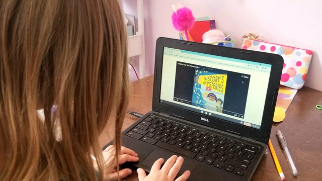 A girl completes a digital learning activity on a computer. 