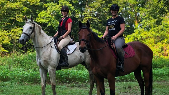 Two girls pose for a photo on horseback along the Brandywine Creek. 