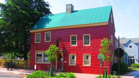 Photo of the Ryves Holt House with small green plants in front of it.