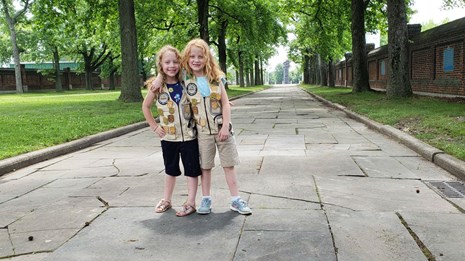 Two kids pose at Fort Christina with their Junior Ranger Badge.