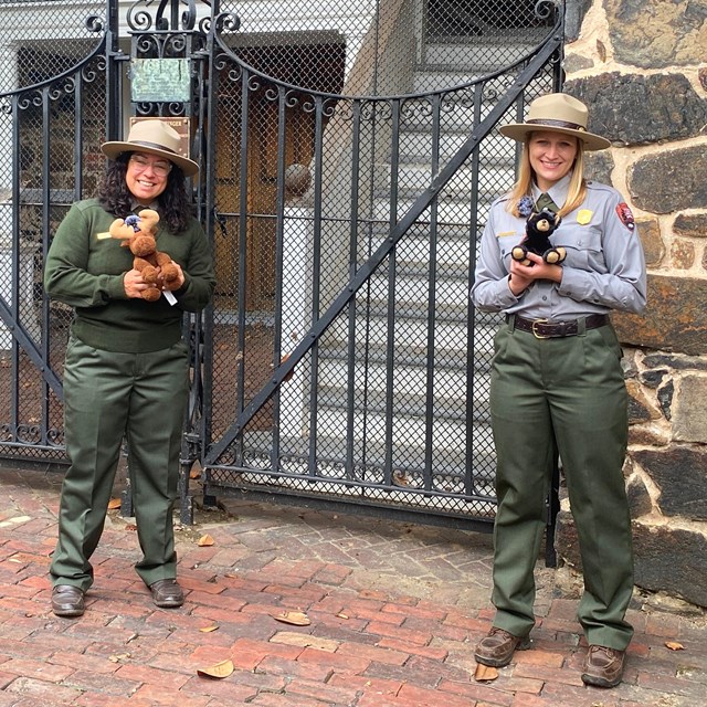 Two park ranger pose with the National Park Expedition Challenge mascots. 