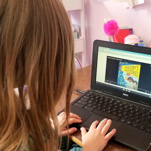 A girl completes a digital learning activity on a computer. 