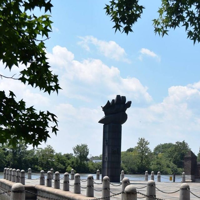 Trees outline the monument at Fort Christina next the the Christina River. 