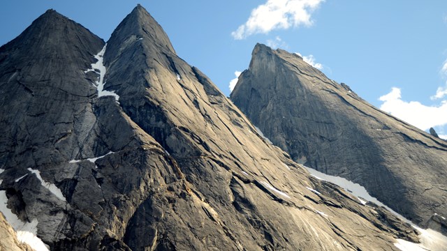 Slate gray granite spires rise against a blue sky