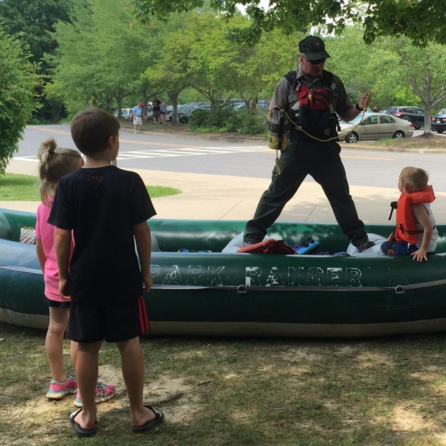 Ranger on raft demonstrating to children