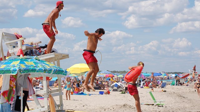 Three lifeguards jumping down from chair