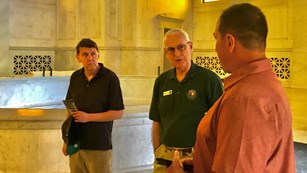 A Volunteer-In-Parks talks with two visitors inside the Mausoleum