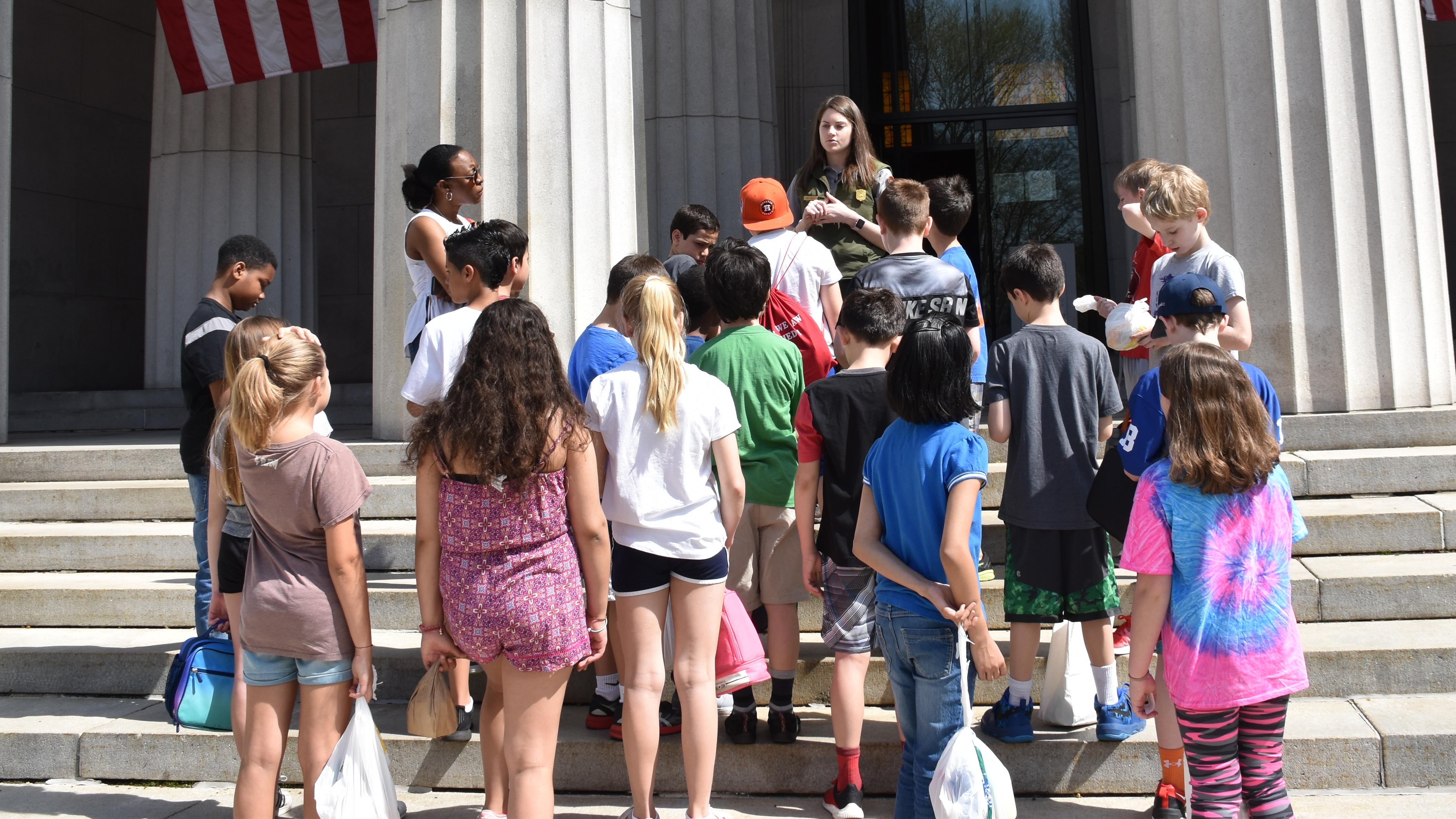 A uniformed Park Ranger talks to a group of students