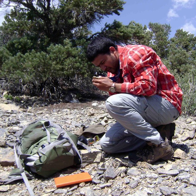 person examining rocks with a magnifying lens 