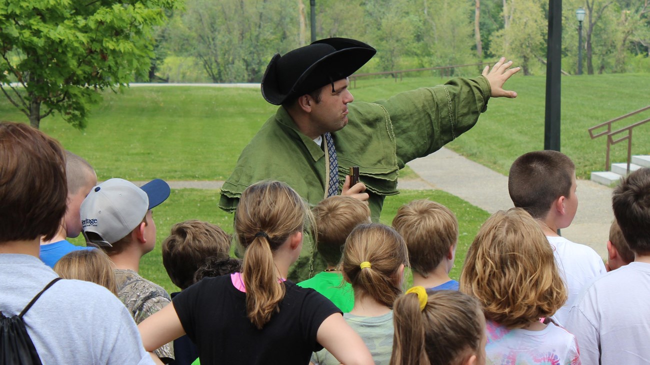 A Ranger in historic dress speaks to a group of school children