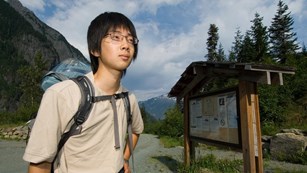 Volunteer in front of trailhead sign