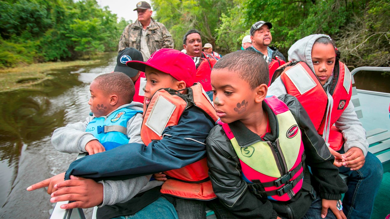 Group of kids in a boat peering at the river