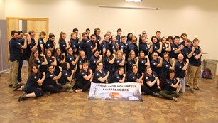 A group of interns stand shoulder to shoulder in blue uniforms