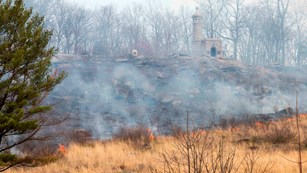 A prescribed fire moves across the western face of Little Round Top from left to right through field