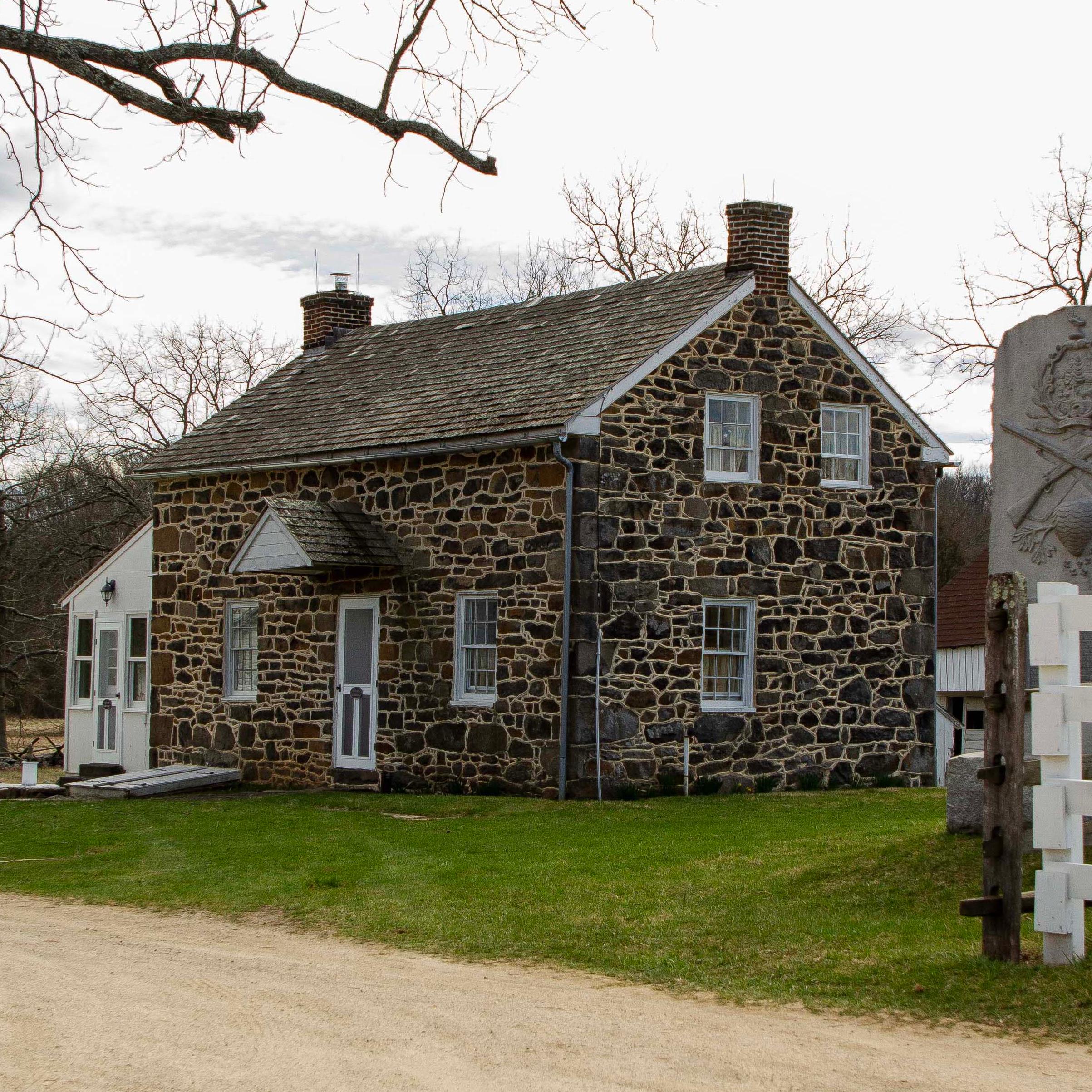 Student program about civilian caught in the crosshairs of battle. Image of stone house.