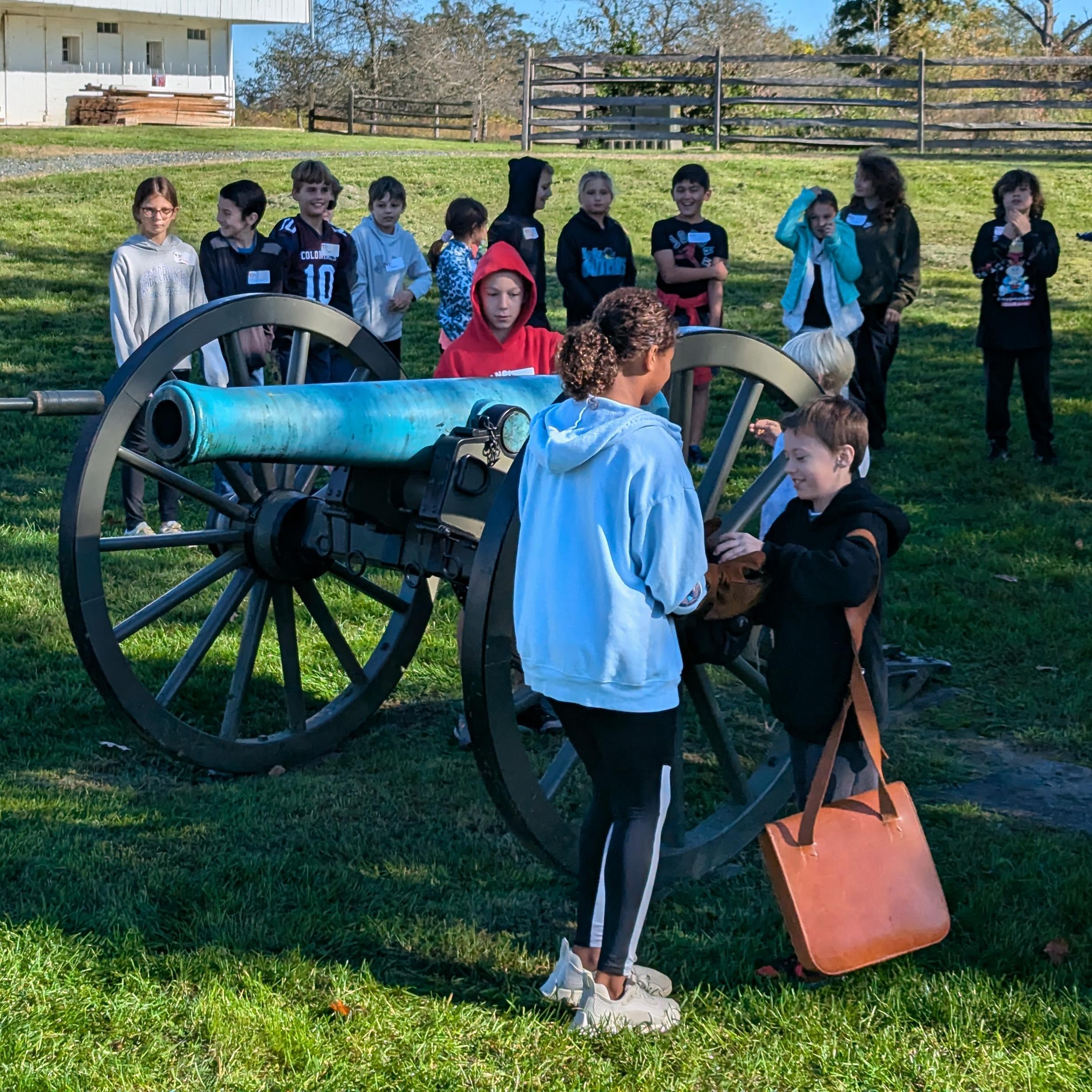 Children listen to a ranger program gathered near a cannon