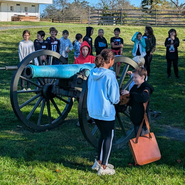 Children listen to a ranger program gathered near a cannon