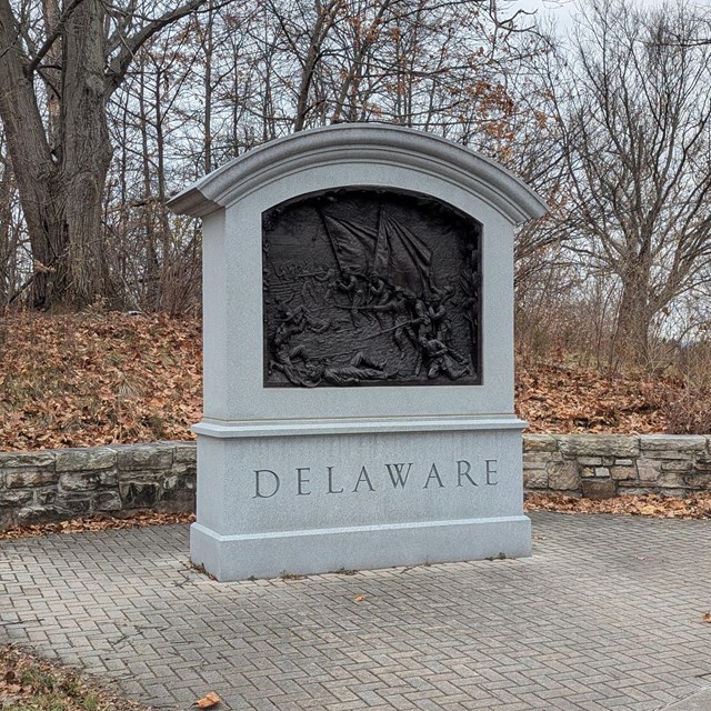 grey stone monument with a bas relief bronze colored plaque, with the word Delaware on the front