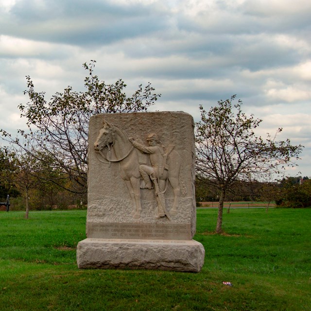 A field with trees and a stone monument