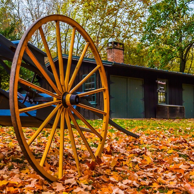 A hand cart rests among the fall leaves next to the Blacksmith Shop in Lower Town