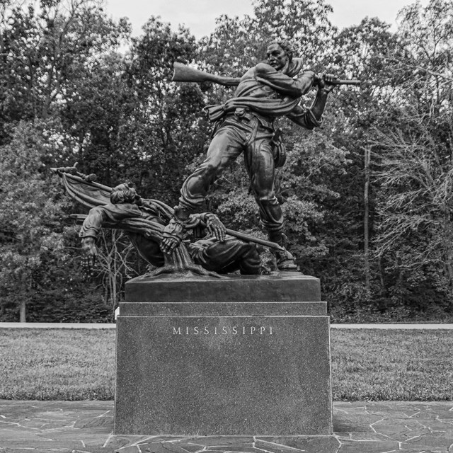 A black and white photo of a monument of a soldier with engraved text reading Mississippi.