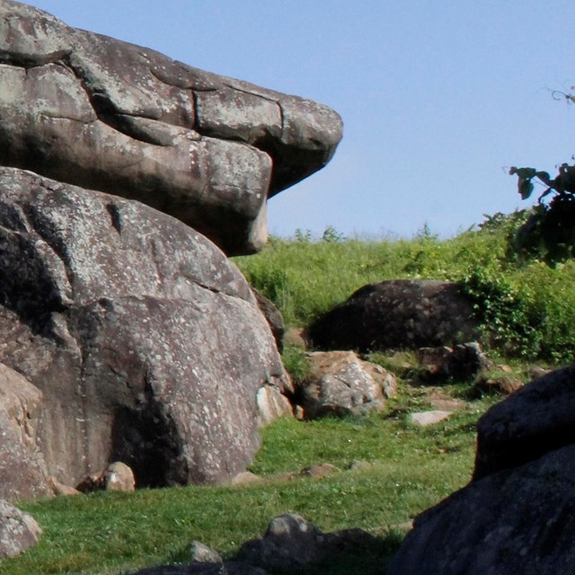 Stacked boulders in a grassy field.