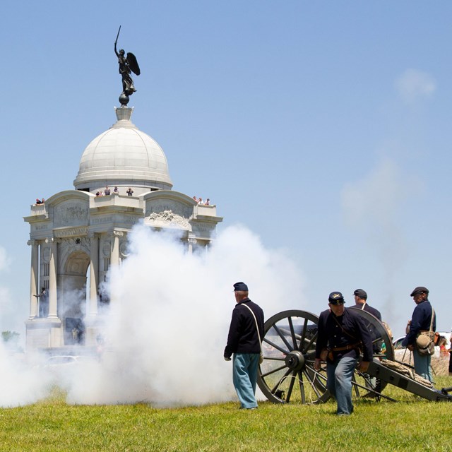 A group of United States soldiers use a cannon in front of the Pennsylvania Memorial. 