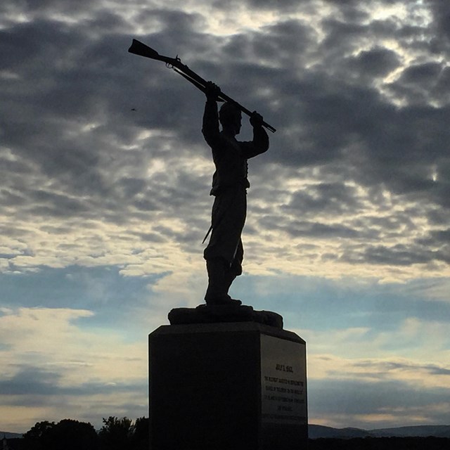 The 72nd Pennsylvania infantry monument is silhouetted against gray clouds.