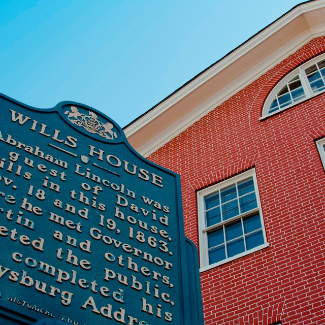 A historical marker in front of a red brick building.