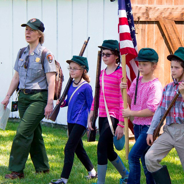 A park ranger marches with students at one of the historic homes on the battlefield.