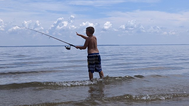 Young man fishing in the surf at the Potomac River Beach.